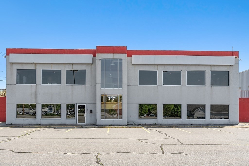 two story cement building with lots of windows and red trim at the roof line.