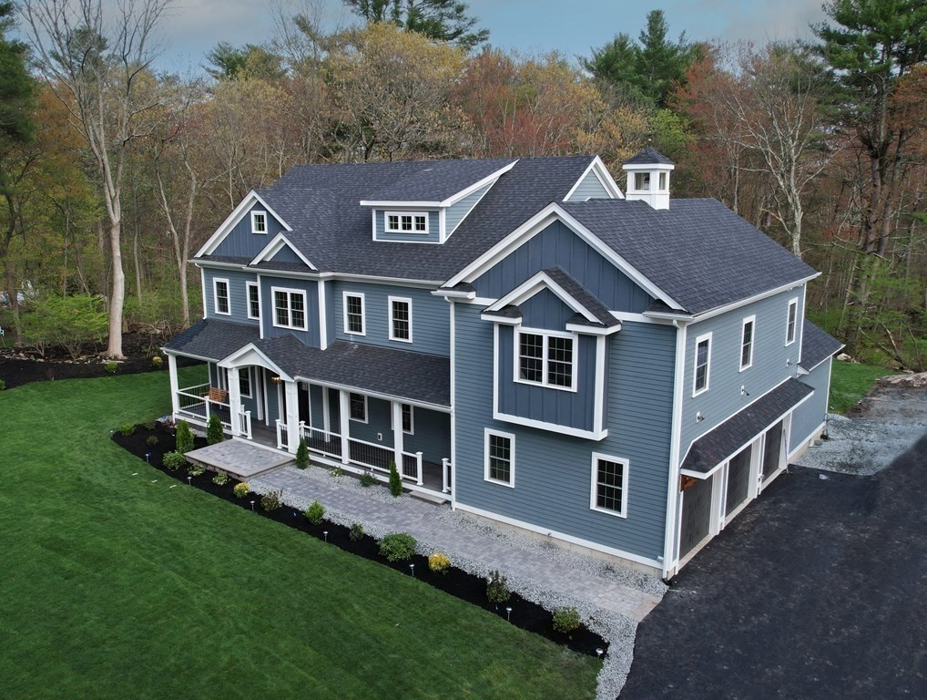 A large 5 bedroom bluish gray colonial style home with white, no shutters and a covered farmers porch.