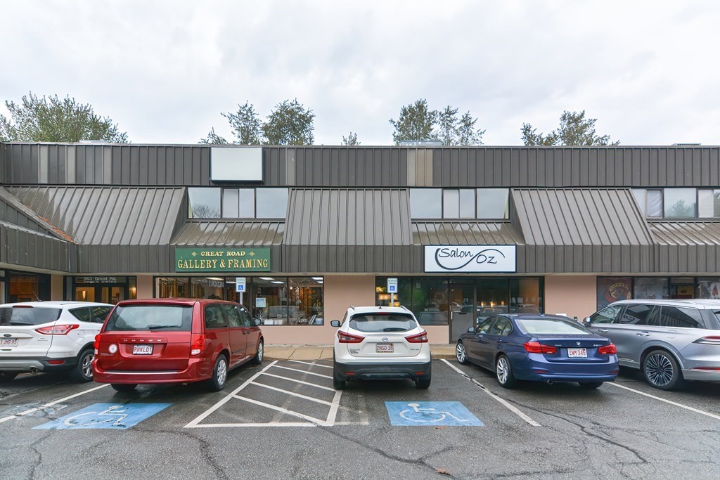 Partial view of a commercial shopping plaza with two businesses labeled on the awning - Salon Oz and Great Road Gallery & Framing