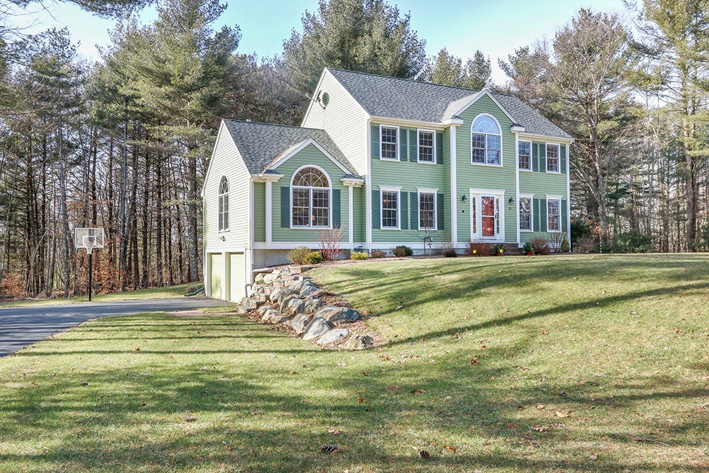 light green colonial style home surrounded by trees