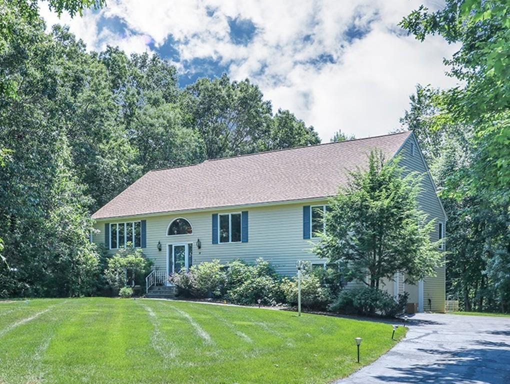 detached beige contemporary style home surrounded by trees, a partly cloudy sky and lawn