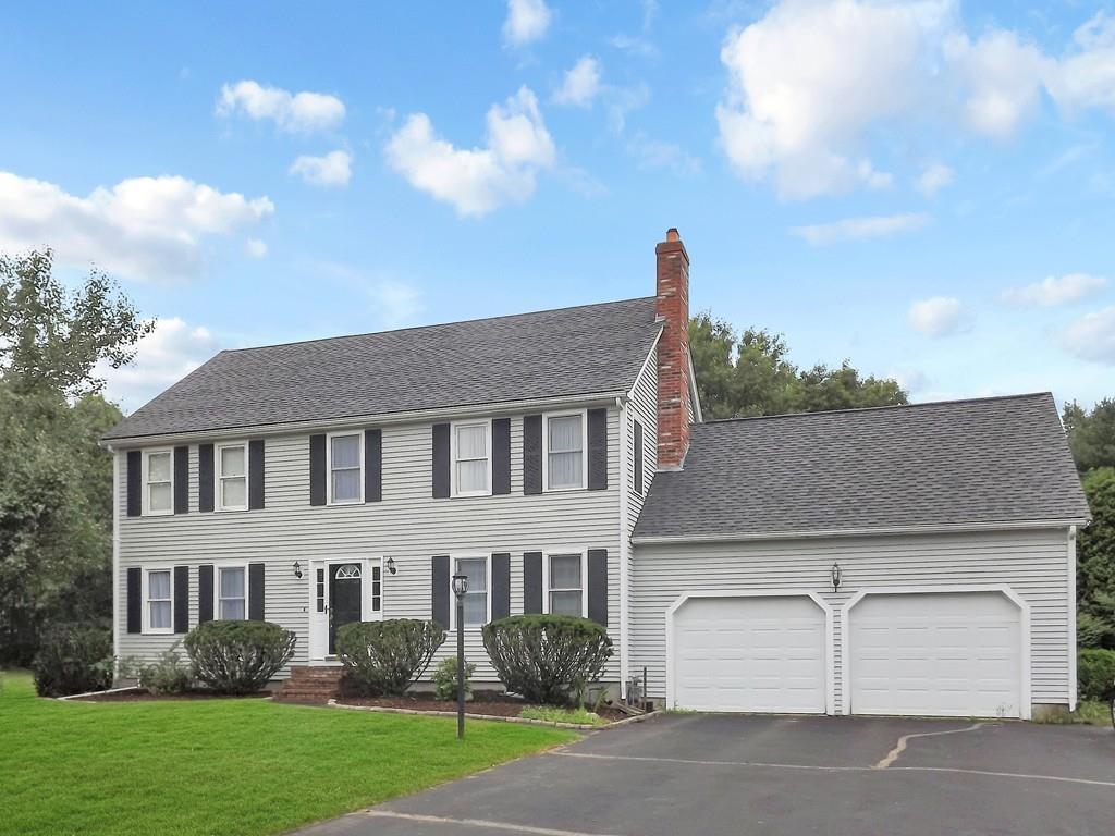 detached gray colonial style home with two white garage doors surrounded by water and a beautiful sky