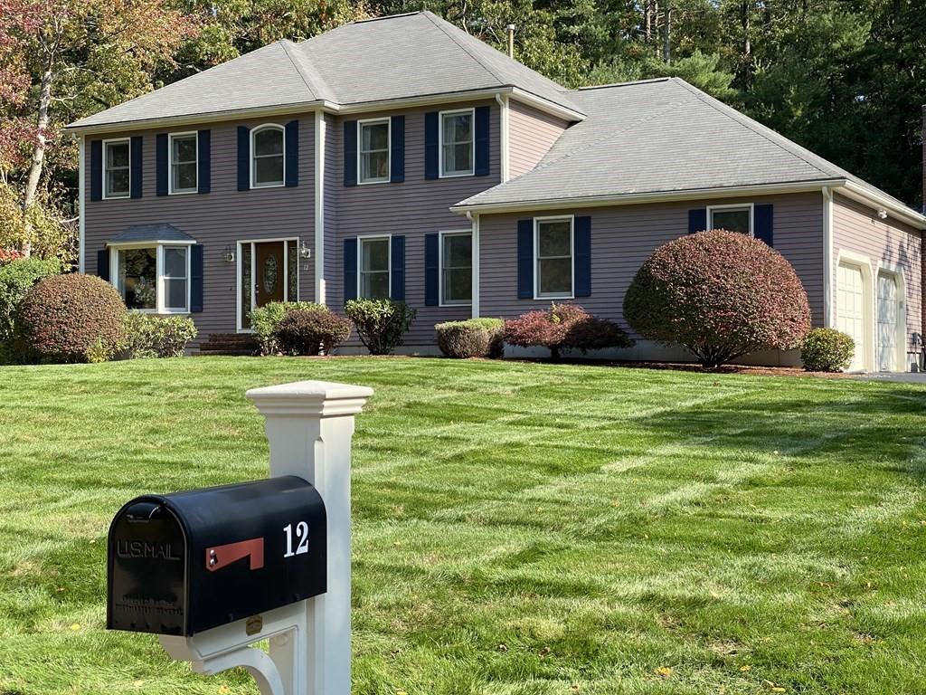 detached lilac colored contempory colonial style home surrounded by trees and lawn